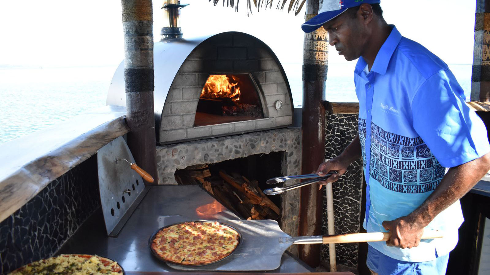 Fijian chef expertly preparing pizza at Seventh Heaven Restaurant